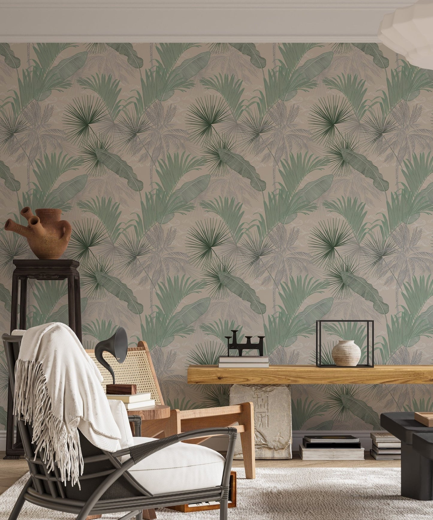Tropical leaves wallpaper in a living area with a black armchair and wooden desk.