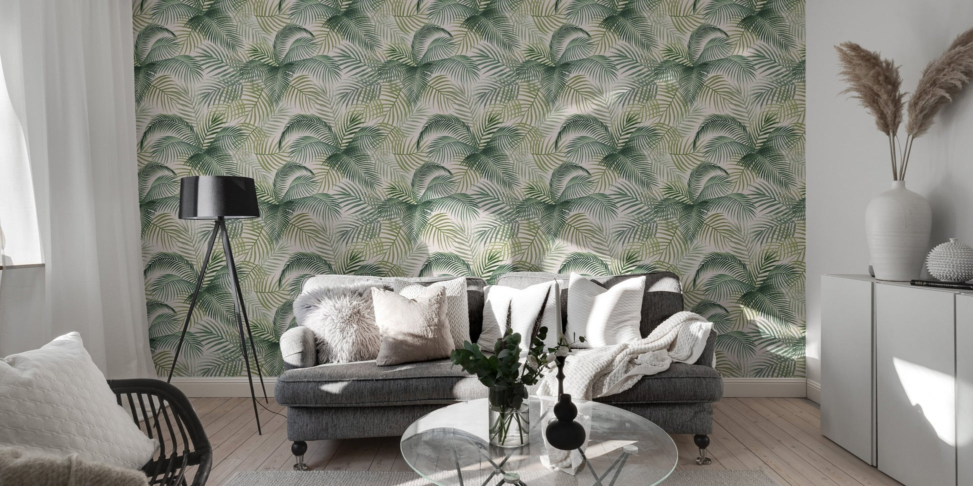 Tropical leaf wallpaper in a spacious living area with a grey sofa and white cabinets.