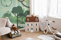 Nursery corner with a dollhouse and botanical tree wall mural in olive tones.