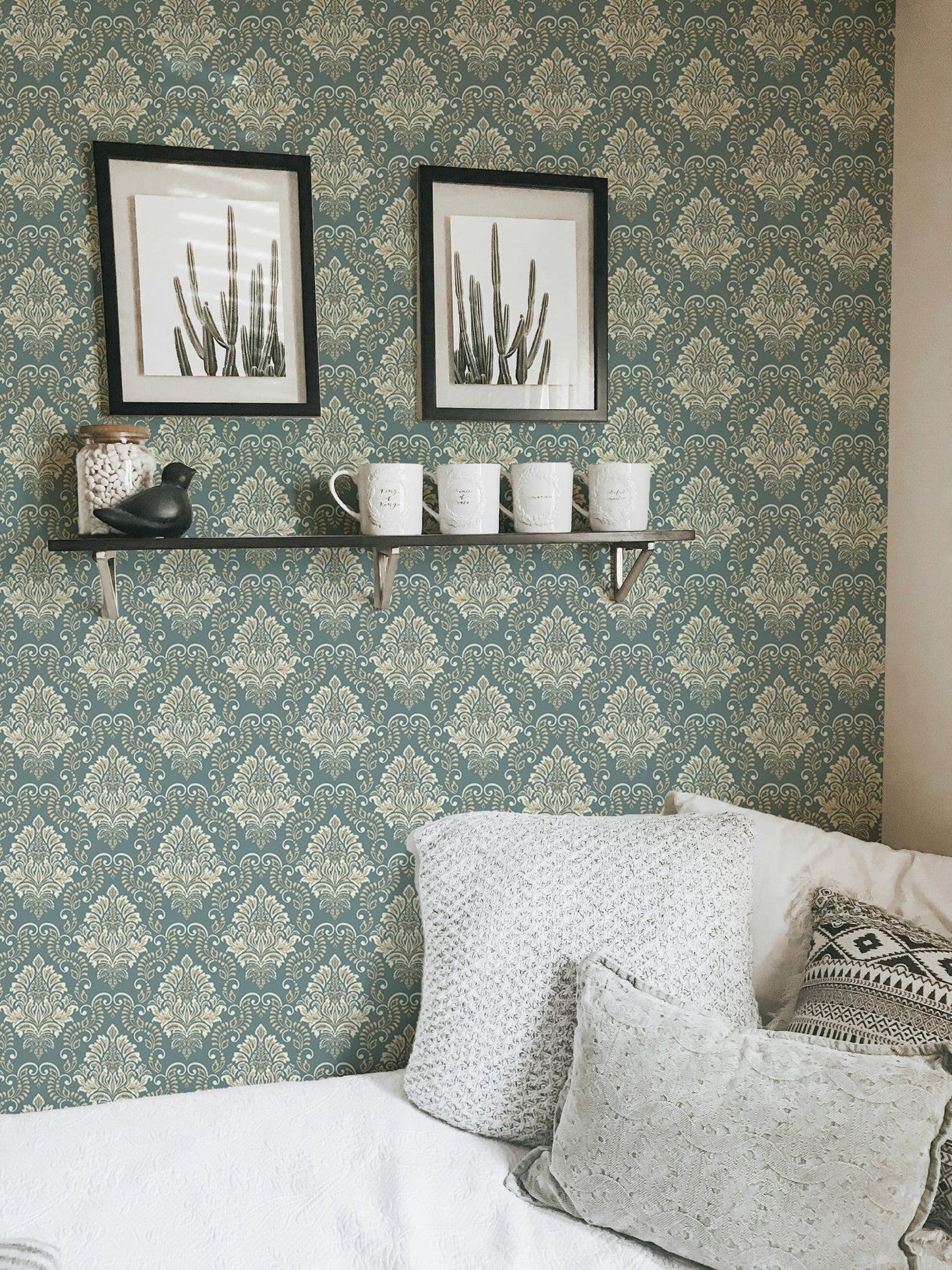 Sage green baroque wallpaper in a living room featuring white pillows and frames.
