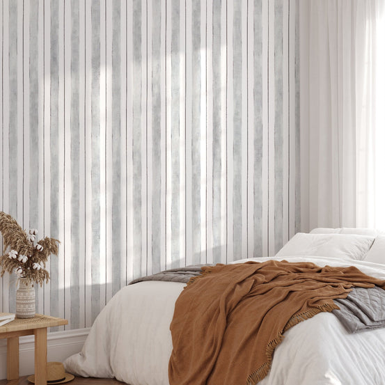 Grey and white striped wallpaper in a bedroom with brown bedding.