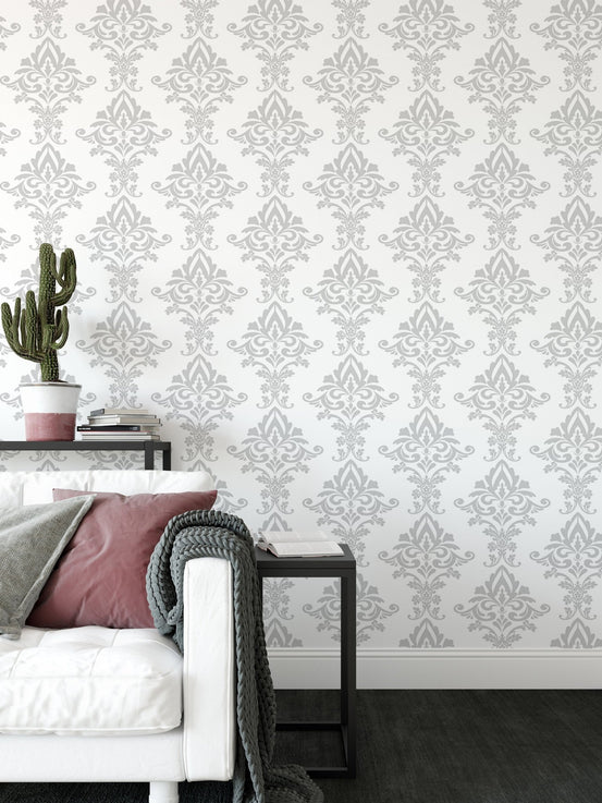 Vintage damask wallpaper behind a white sofa with a black side table in living area.