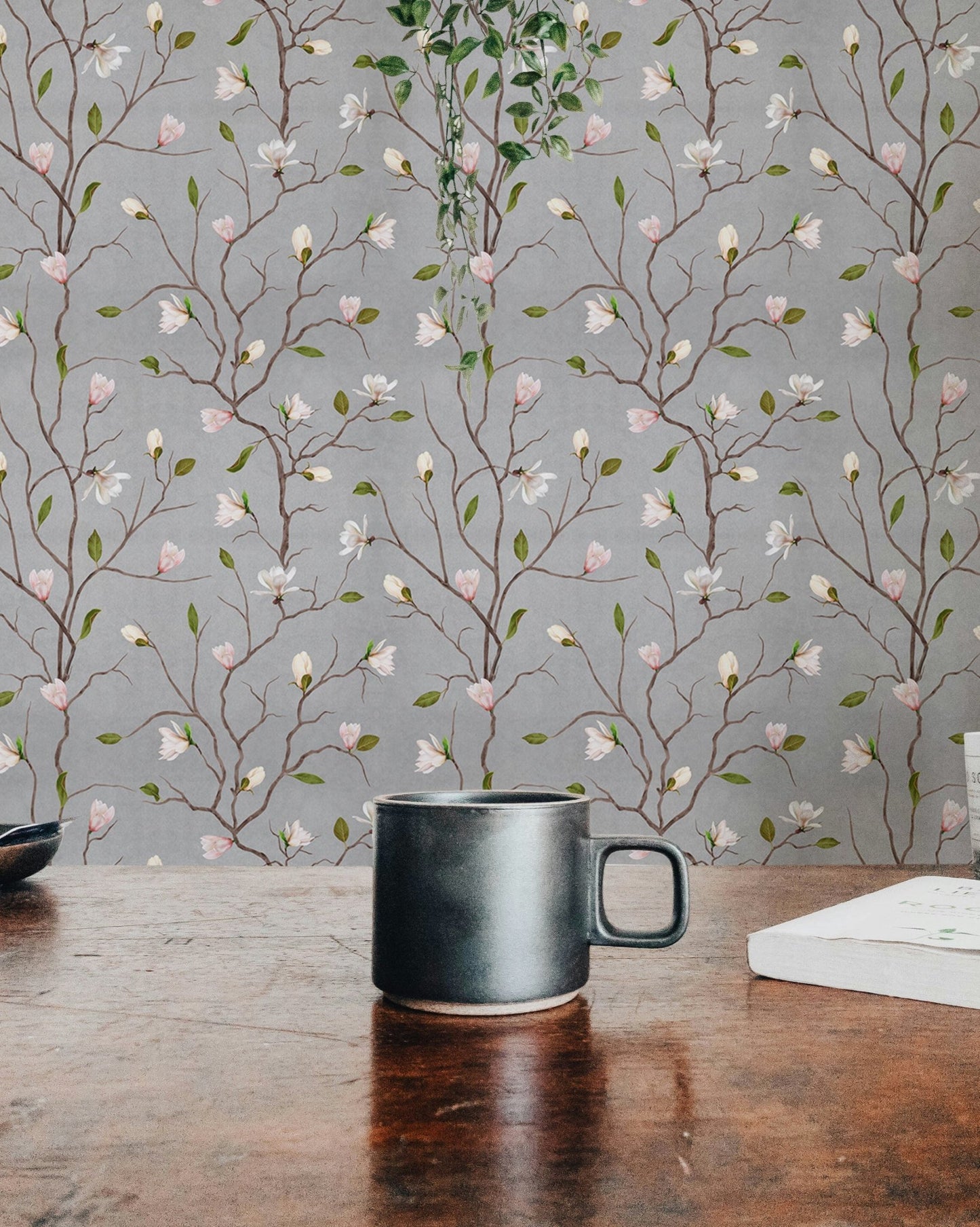 Magnolia tree wallpaper detail behind a wooden desk with a black coffee mug.