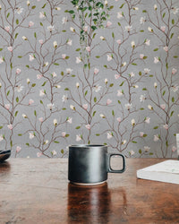 Magnolia tree wallpaper detail behind a wooden desk with a black coffee mug.