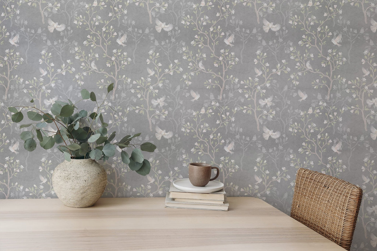 Floral bird wallpaper design on a dining room wall with a light wood table.