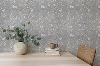 Floral bird wallpaper design on a dining room wall with a light wood table.