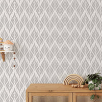 Grey color leaves damask design wallpaper behind a wooden sideboard.