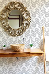 Damask design wallpaper in a bathroom with a round mirror and wood sink.