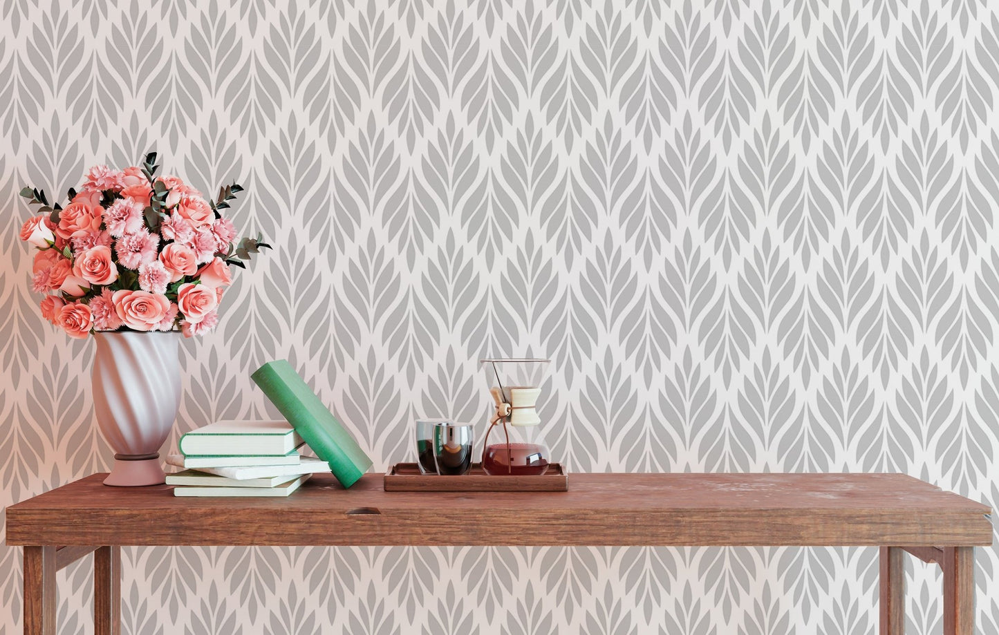 Geometric leaves wallpaper behind a wooden table with pink flowers.