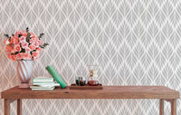 Geometric leaves wallpaper behind a wooden table with pink flowers.
