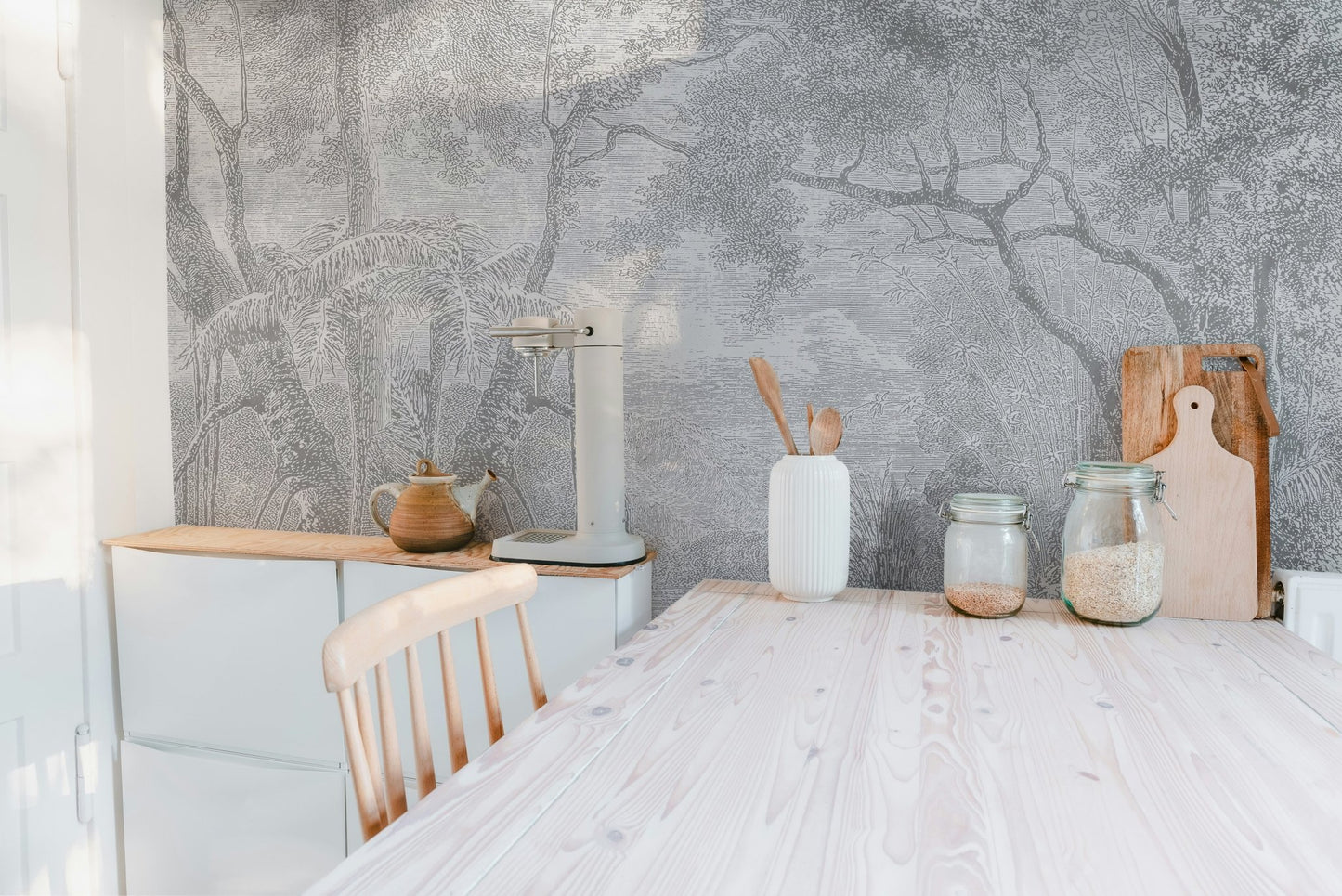 Monochrome forest sketch wall mural behind a white kitchen dining table.