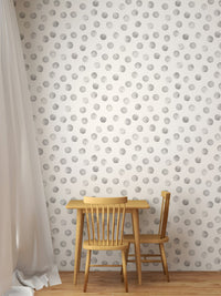 Small wooden table and chairs against a grey polka dot wallpaper.