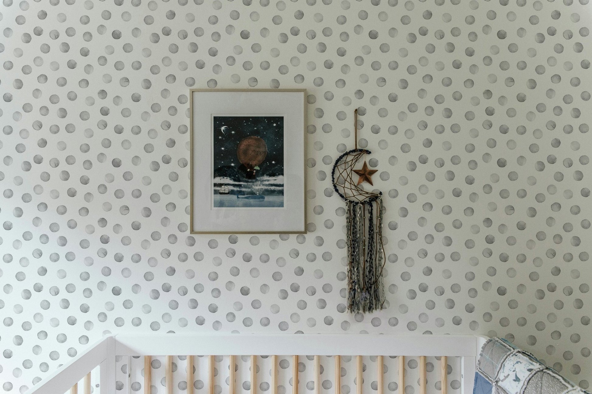 Nursery with white crib and grey polka dot wallpaper.