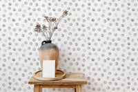 Decorative vase on stool with grey polka dot pattern wallpaper.