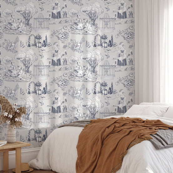 Neutral bedroom wallpaper with grey toile print and a terracotta throw blanket.