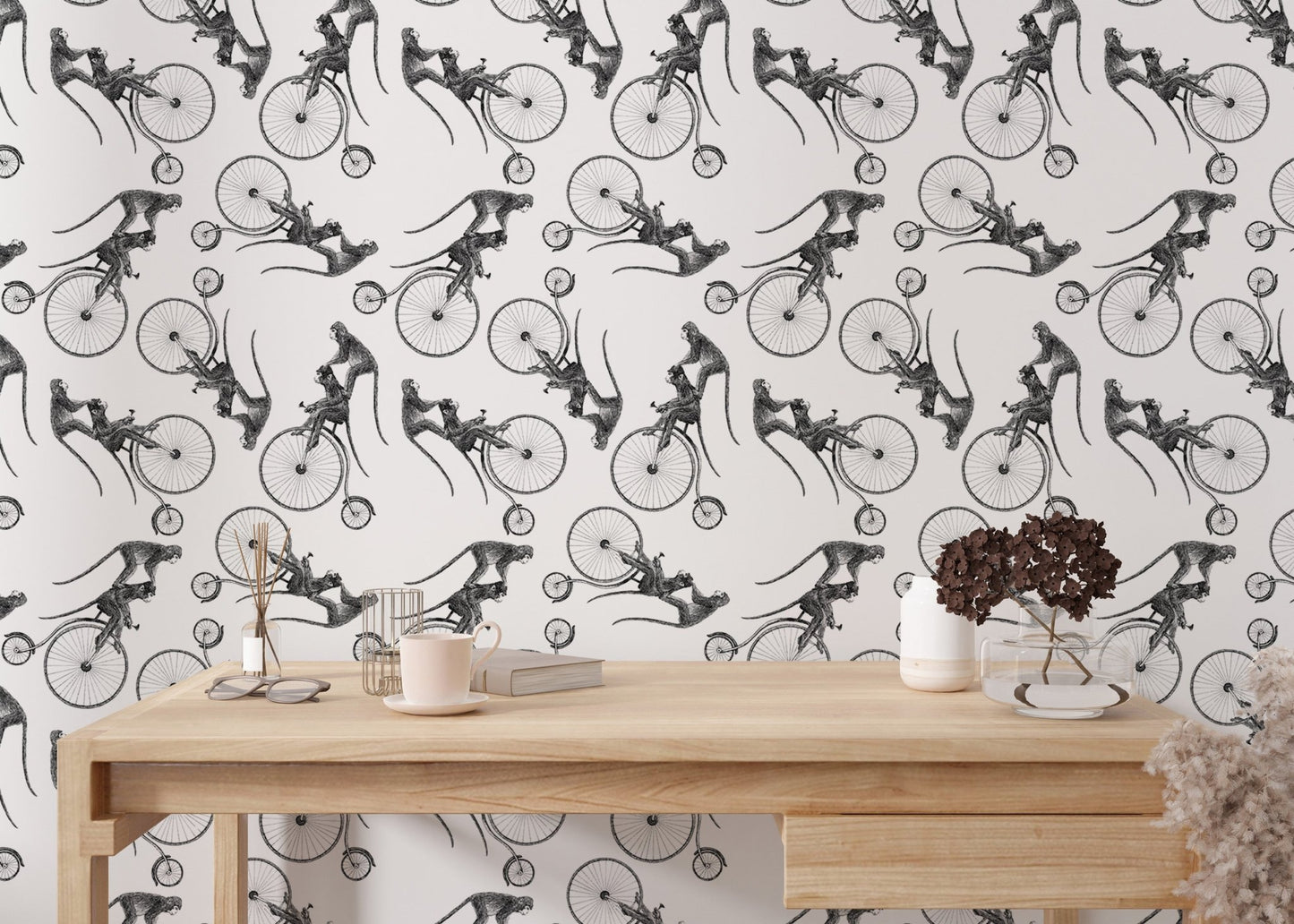 Minimalist monkey bicycle wallpaper on a wall behind a light wood office desk.