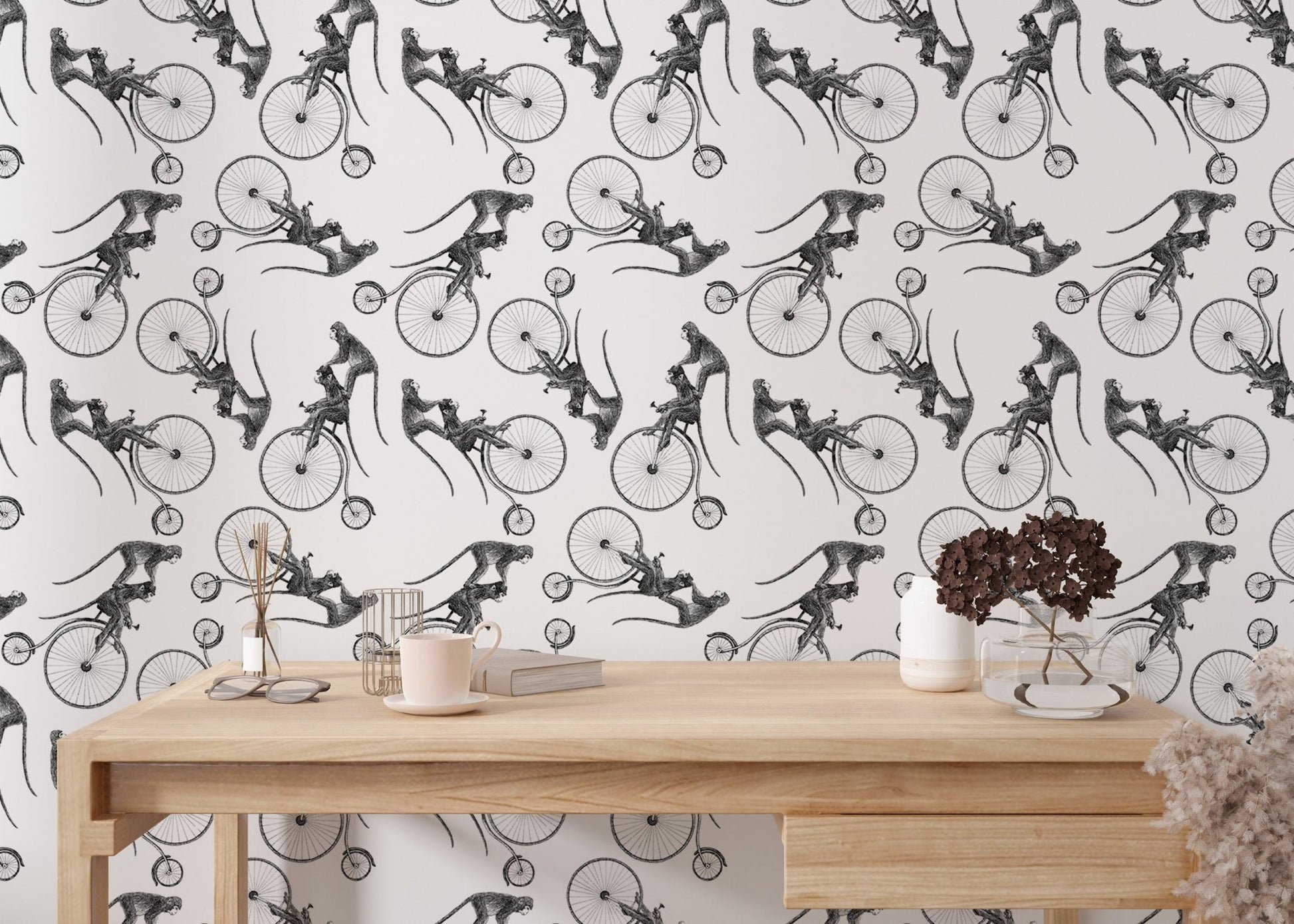 Minimalist monkey bicycle wallpaper on a wall behind a light wood office desk.