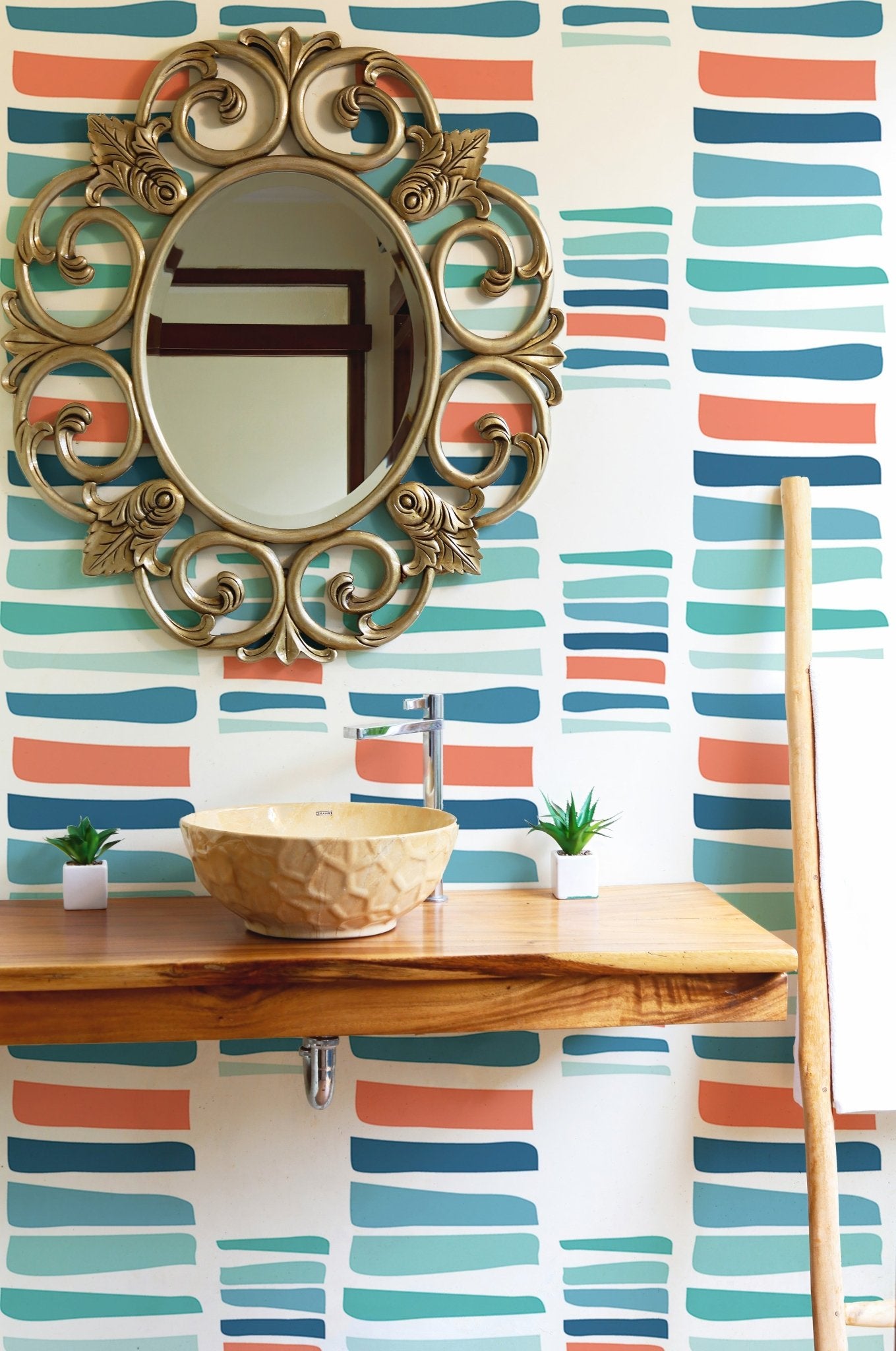 Vibrant maritime stripe wallpaper in a bathroom behind a wooden vanity and mirror.
