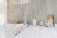 Neutral leaves pattern wall mural behind a wooden dining table and kitchen jars.