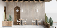 Outdoor cafe seating with a beige leaf wall mural and desert plants.