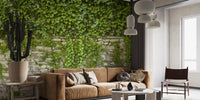 Lush green vine wall mural behind a brown leather sofa in a bright living room.