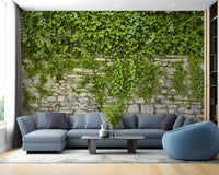 Realistic green leaf wallpaper mural in a living area with a blue sectional sofa.