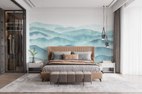 Minimalist bedroom with blue wave pattern wall mural behind a wooden bed.