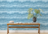 Indigo wavy stripe wallpaper in a sunlit room with indoor plants and a bench.