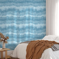 Textured blue marine wallpaper in a bright bedroom with white bedding.