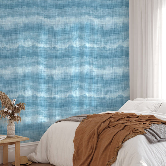 Textured blue marine wallpaper in a bright bedroom with white bedding.