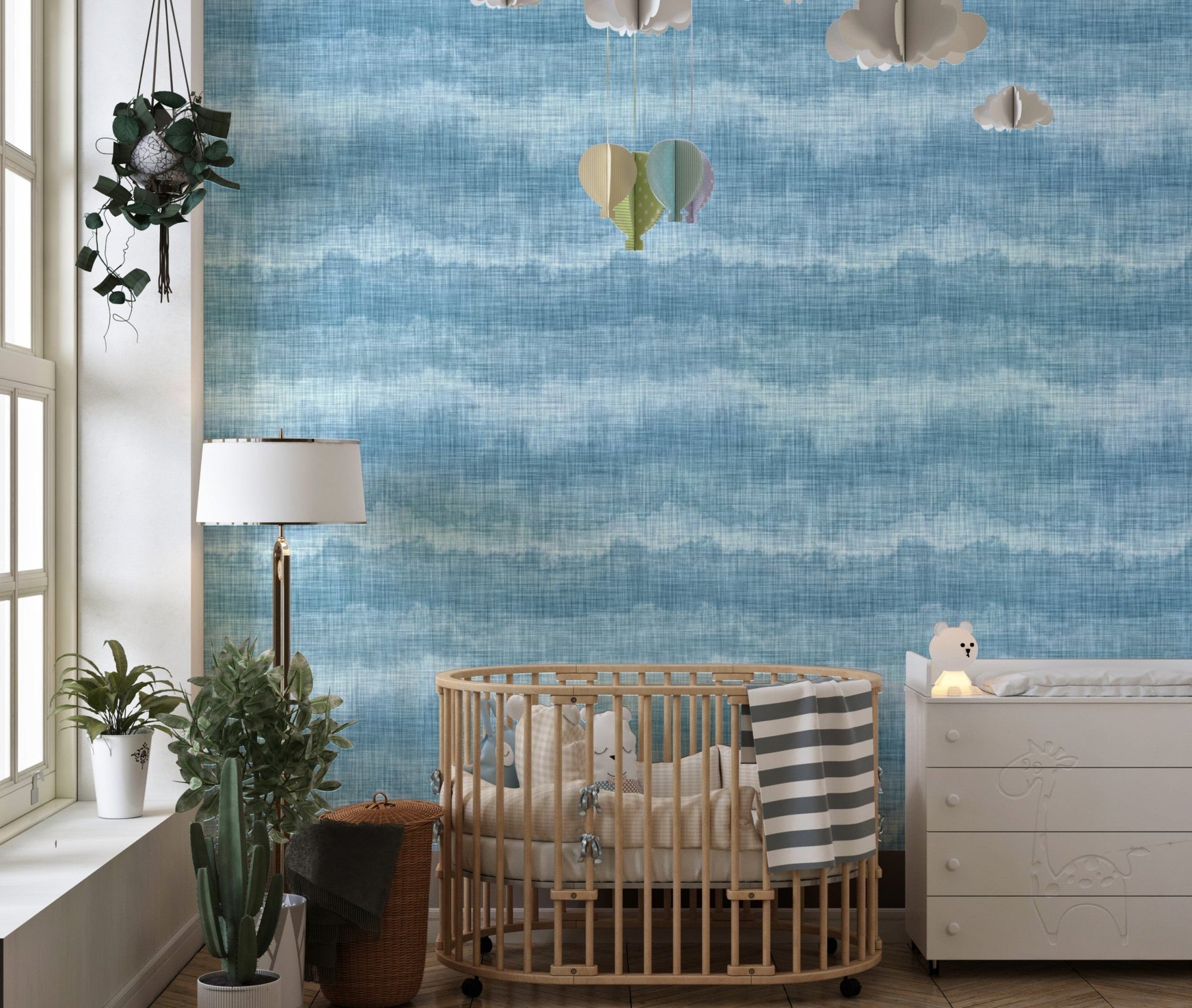 Indigo blue wavy stripe wallpaper in a nursery with a round wooden crib.