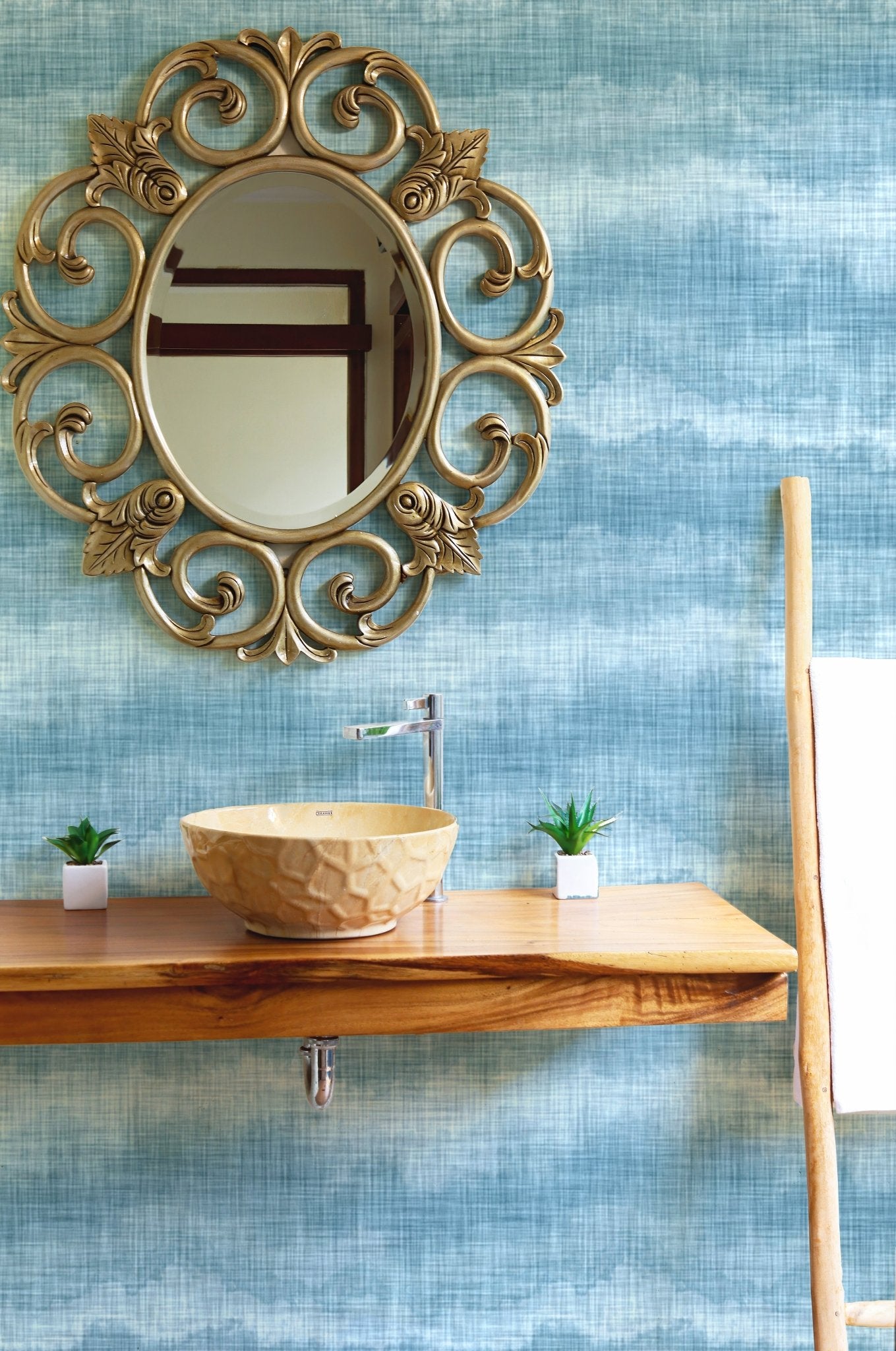 Textured marine wallpaper in a bathroom with a gold mirror and wooden vanity.