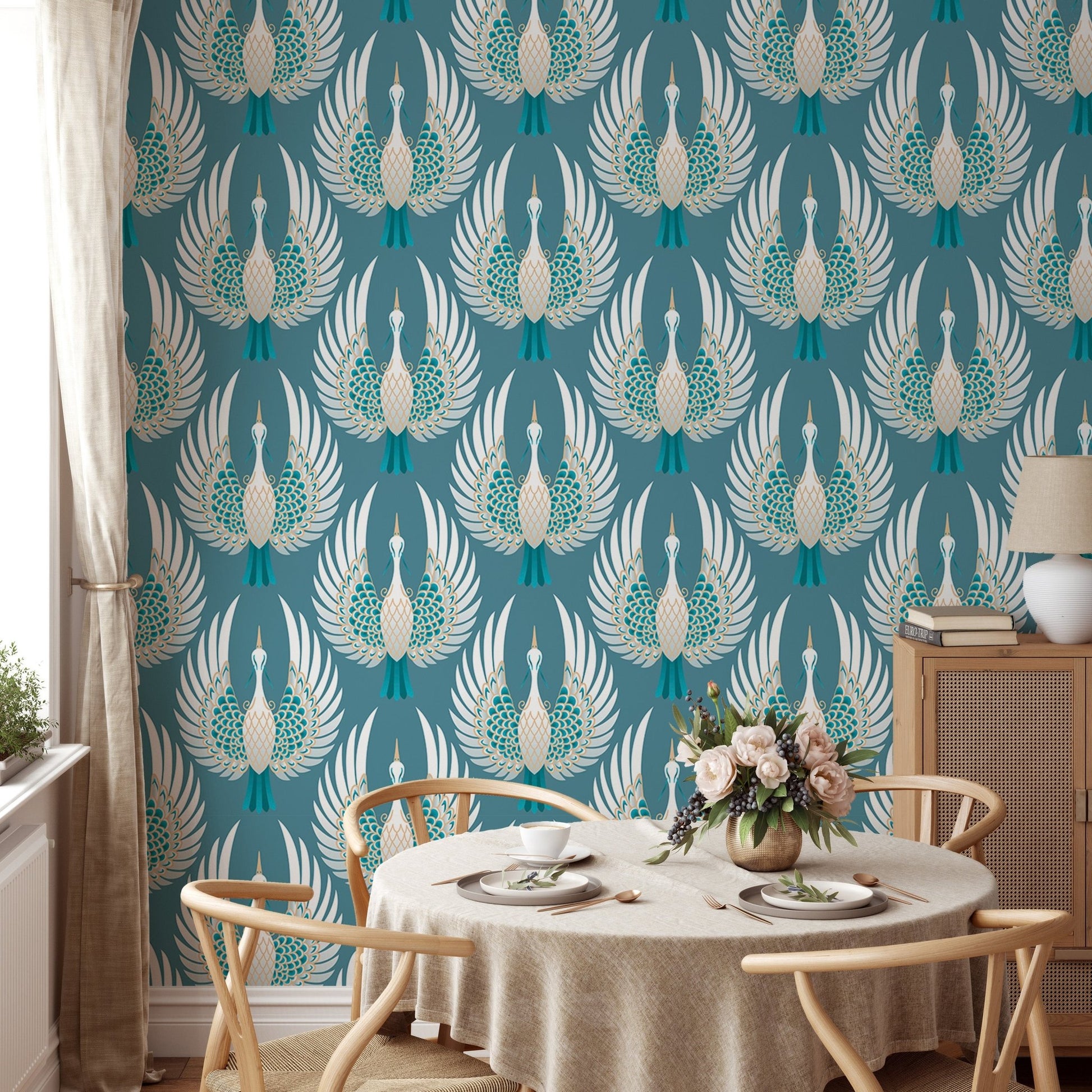 Teal bird wallpaper in a dining room with a round wooden table and chairs.