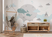 Playroom wall mural featuring whales and clouds behind a wooden rocking chair