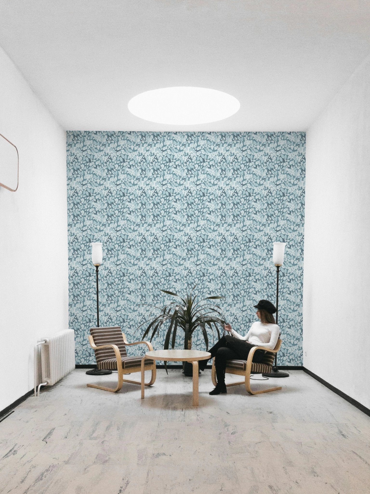 Minimalist white room with a blue leaf wallpaper focal point.