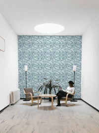 Minimalist white room with a blue leaf wallpaper focal point.