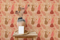 Home office wall with peach background vase and leaf print wallpaper.