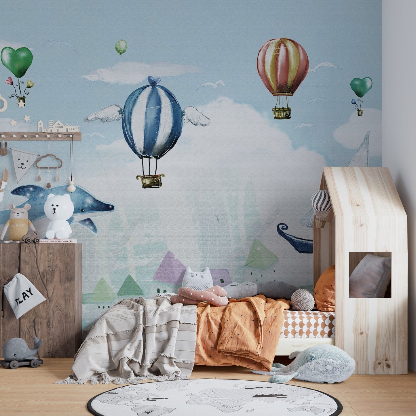 Flying whale and striped balloon wall mural behind a wooden crib in kids bedroom.