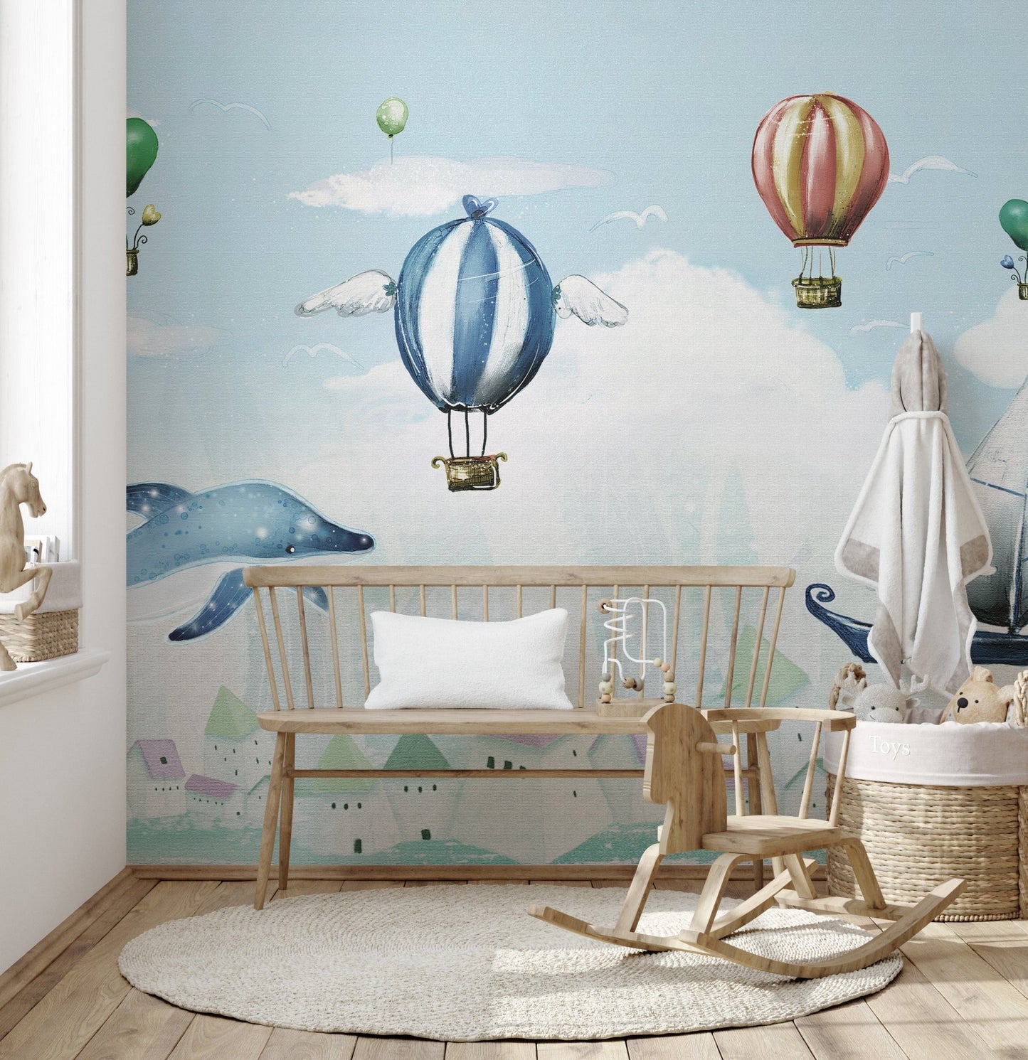 Hot air balloon and whale wall mural in a bright nursery room.