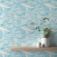 Blue wave and white whale wallpaper behind a wooden shelf and potted plant.