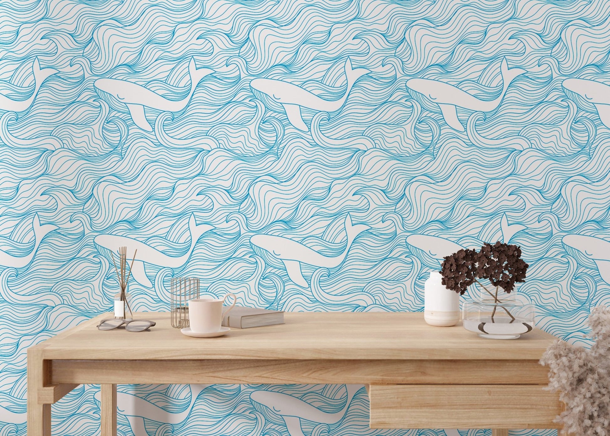 Light blue whale wallpaper on a study wall behind a light wood desk.