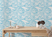 Light blue whale wallpaper on a study wall behind a light wood desk.