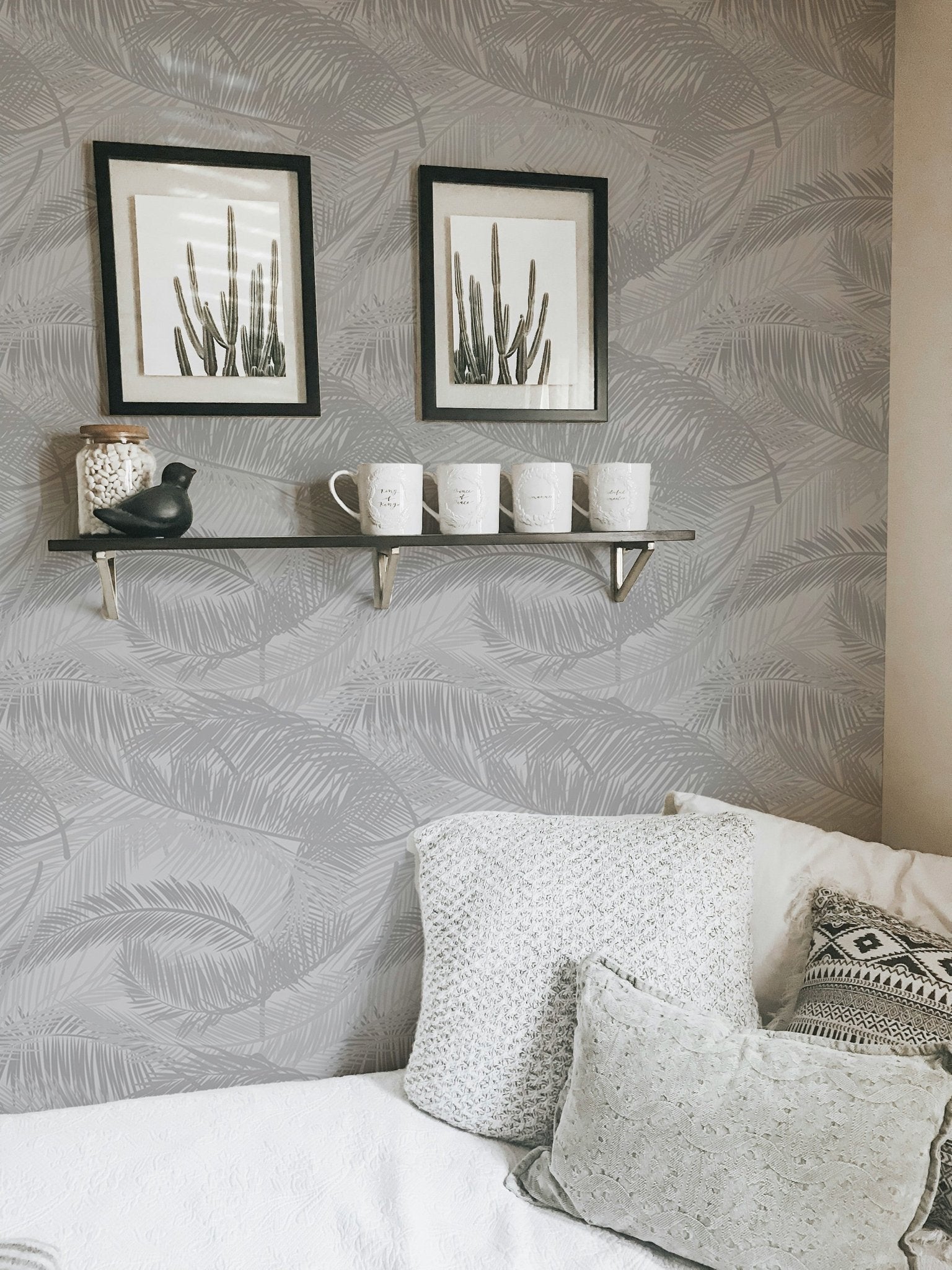 Living room corner with sofa and light gray palm leaves silhouette wallpaper.