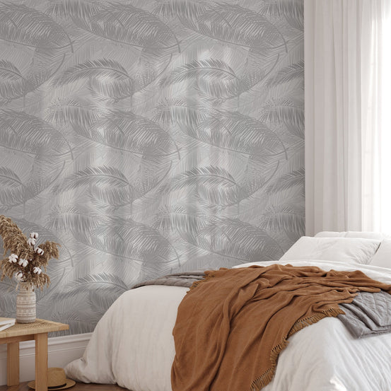 Airy bedroom decor featuring silhouette leaf pattern wallpaper on a feature wall.
