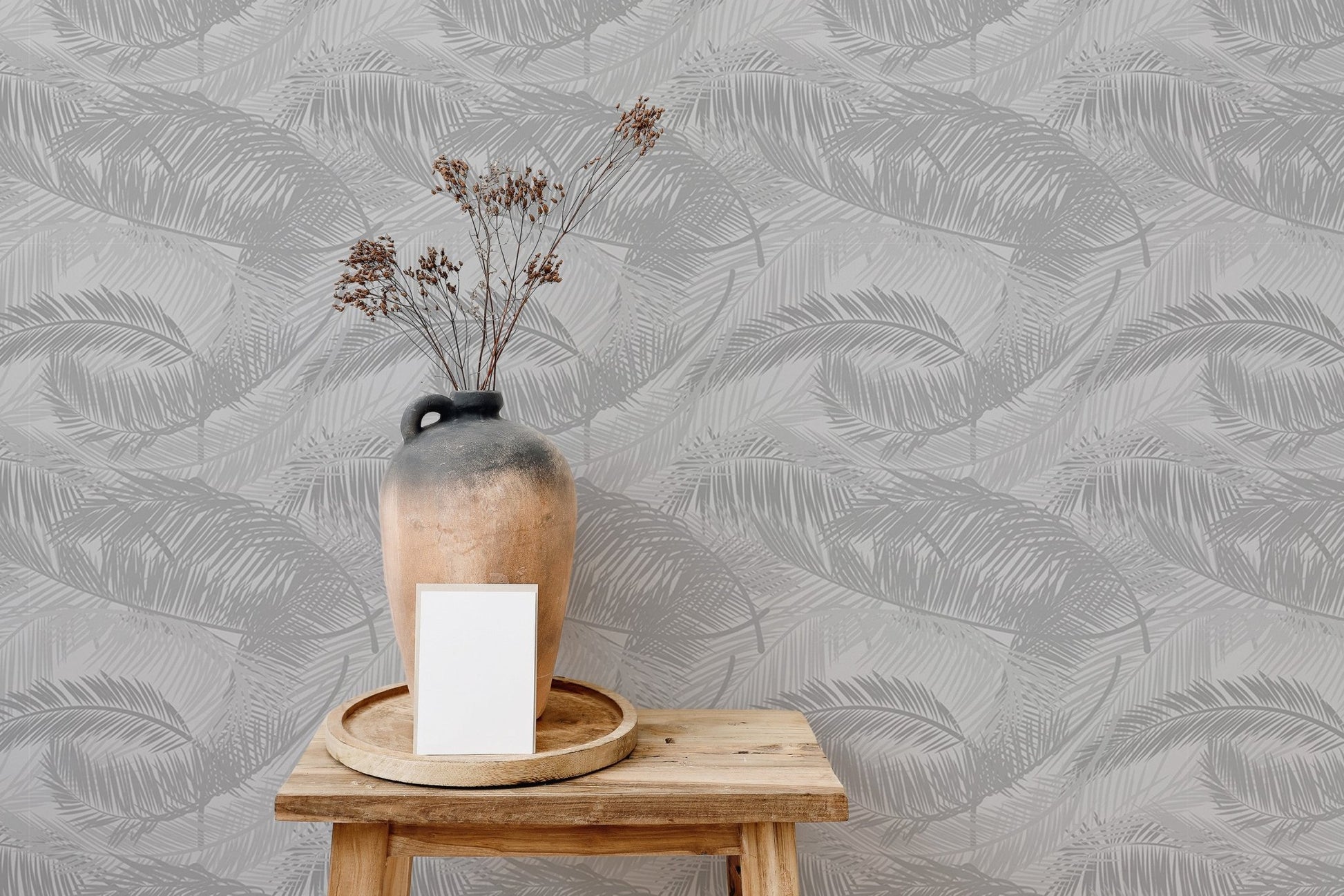 Decorative wooden stool with vase against light gray palm leaves wallpaper.