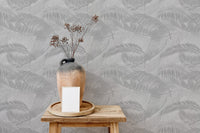 Decorative wooden stool with vase against light gray palm leaves wallpaper.