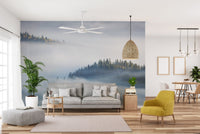 Modern living area with yellow accent chair and misty forest wallpaper mural.
