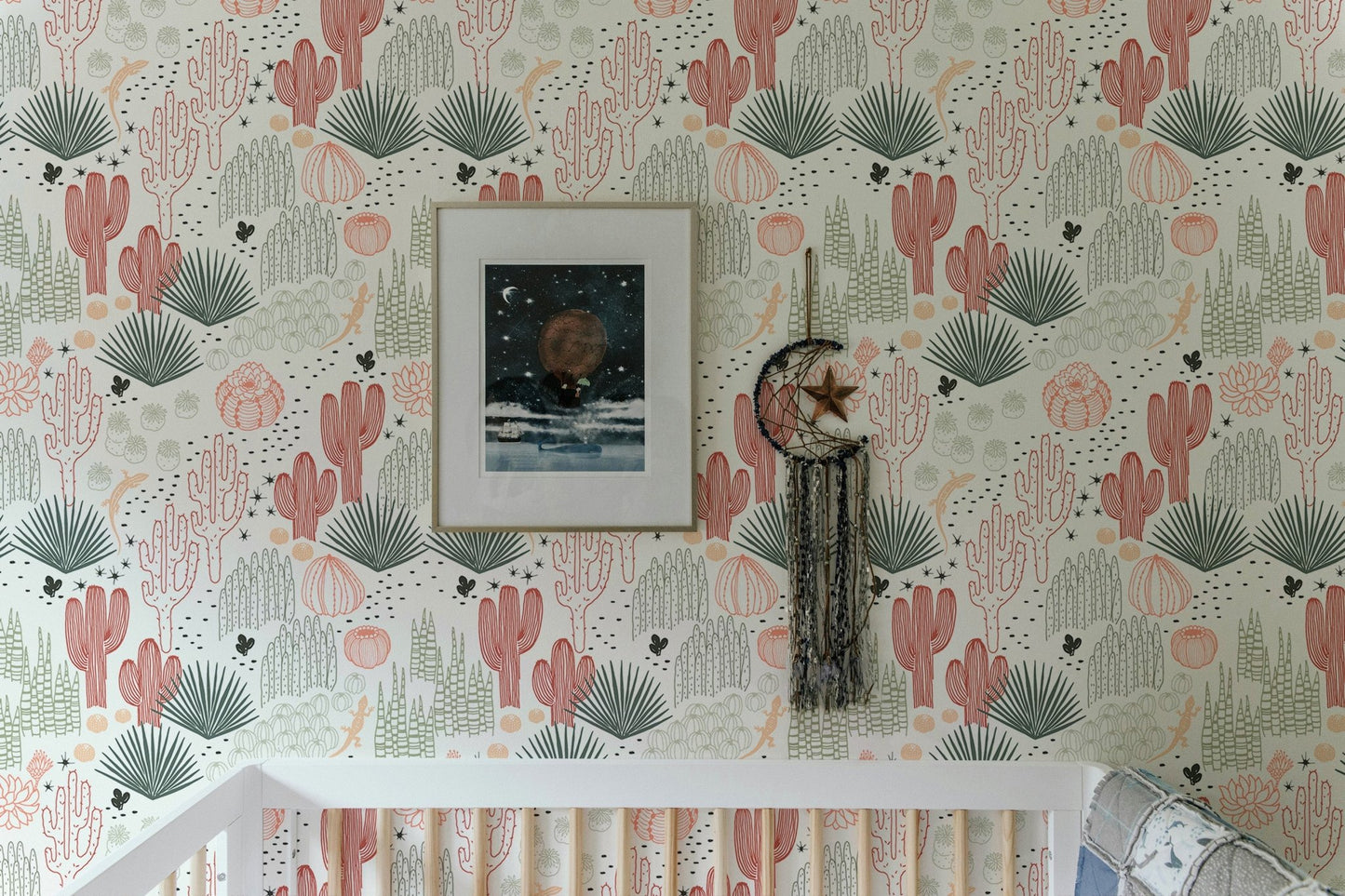 Wallpaper with cacti and lizards above a white crib in a bright nursery.