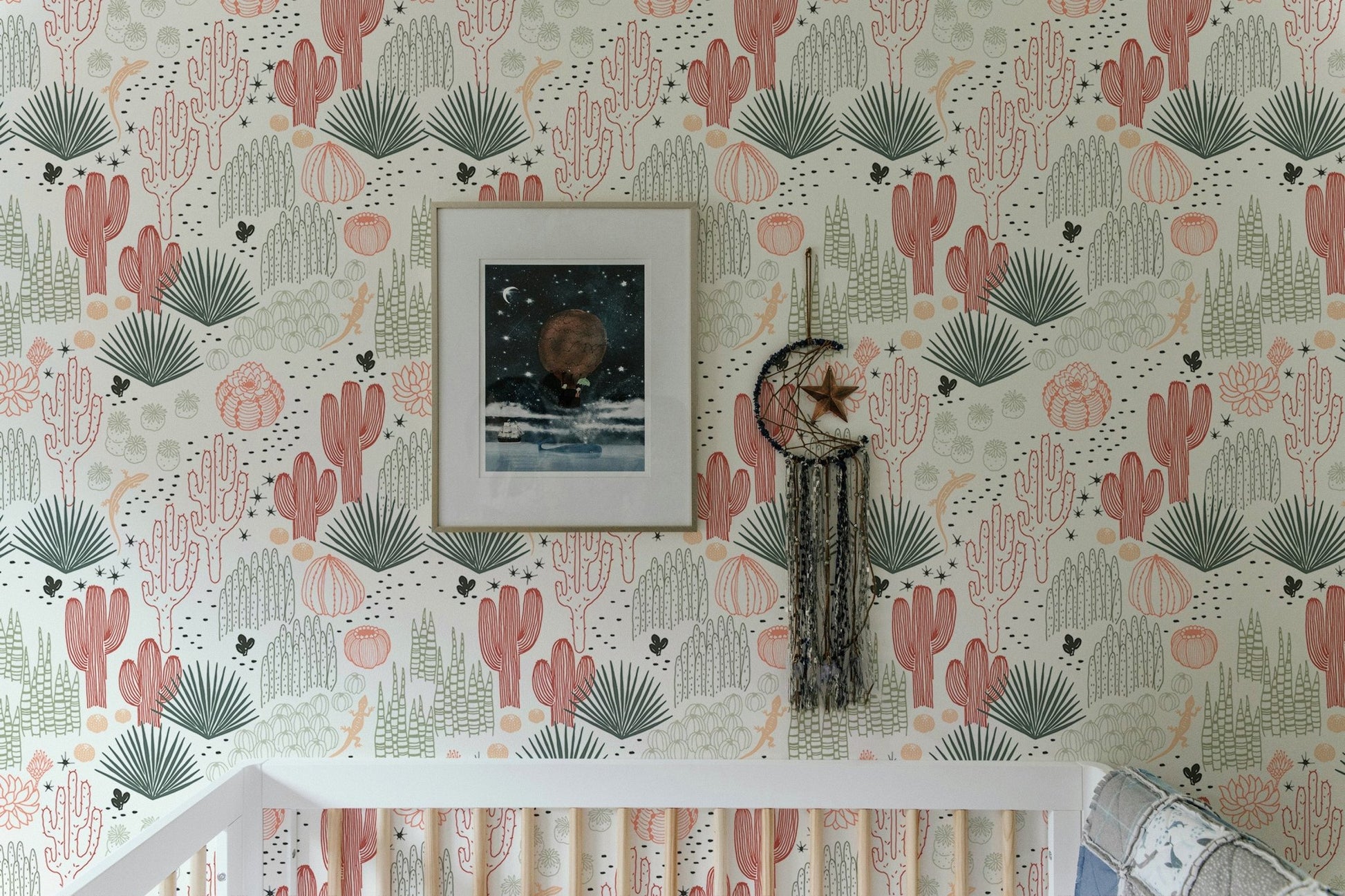 Wallpaper with cacti and lizards above a white crib in a bright nursery.