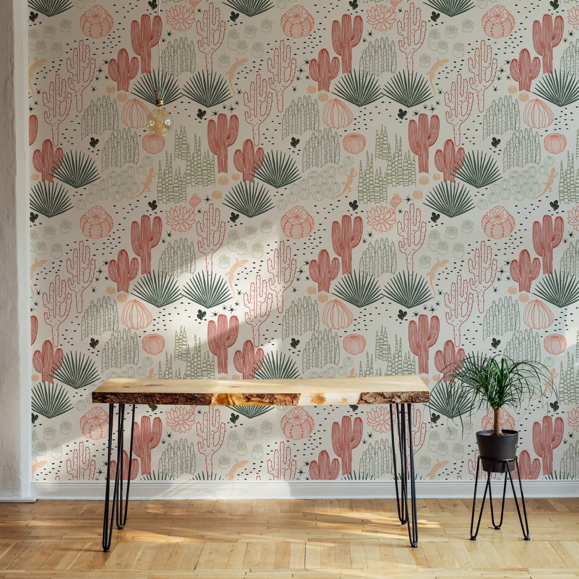 Minimalist desk area with Mexican cacti wallpaper and a small green plant.